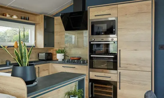 Modern kitchen and breakfast bar fitted with contemporary natural wood cupboard doors and dark blue walls