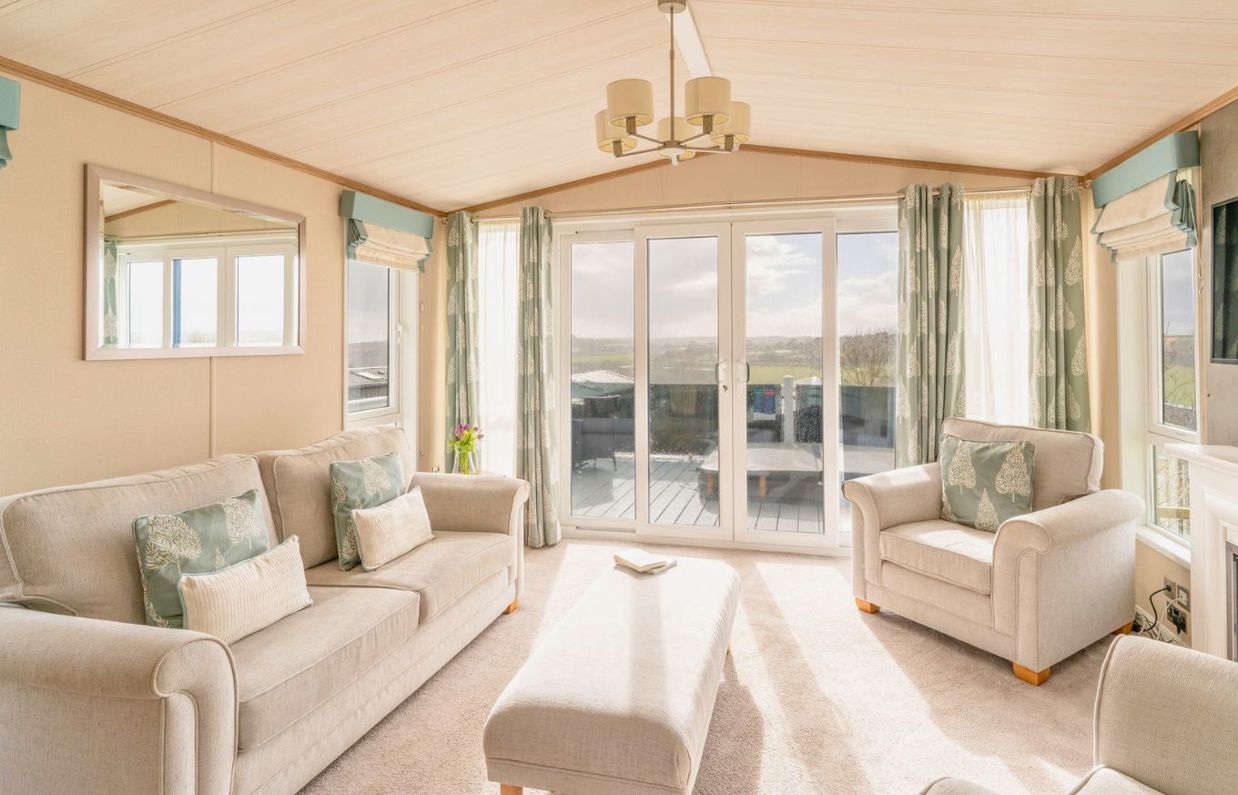 Internal of a caravan open plan living space with sliding doors onto decking with hot tub and countryside views