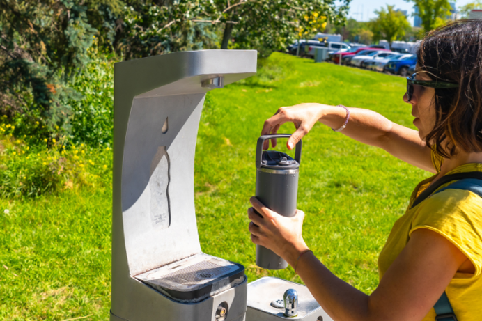 Using a reusable water bottle to fill up at a fountain in the sun