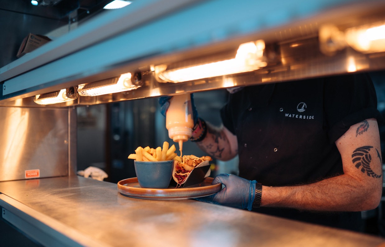 A chef adding the sauce to a dish at the serving counter of Drift Bar & Grill