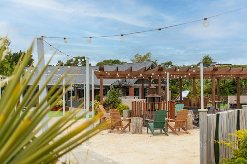 Outdoor seating at Stargazy with a fire pit under a veranda and fairy lights