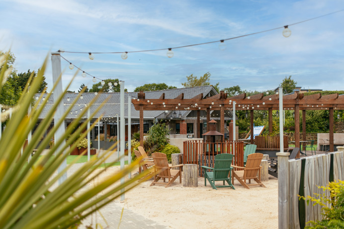 Outdoor seating at Stargazy with a fire pit under a veranda and fairy lights