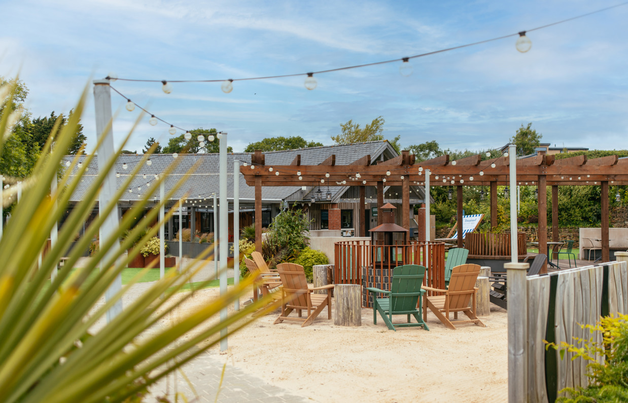Outdoor seating at Stargazy with a fire pit under a veranda and fairy lights