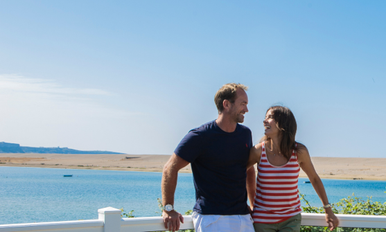 Couple on deck at Chesil Beach Holiday Park with sea and beach behind them