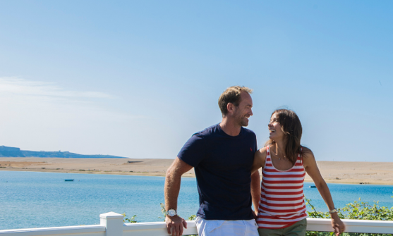 Couple on deck at Chesil Beach Holiday Park with sea and beach behind them