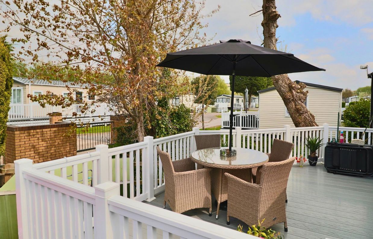 External of a caravan on pitch with decking and outdoor furniture