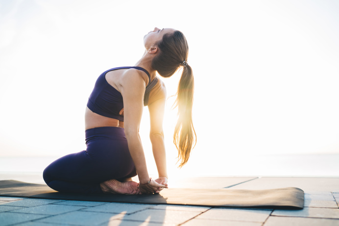 A woman stretching on a yoga mat in the sun