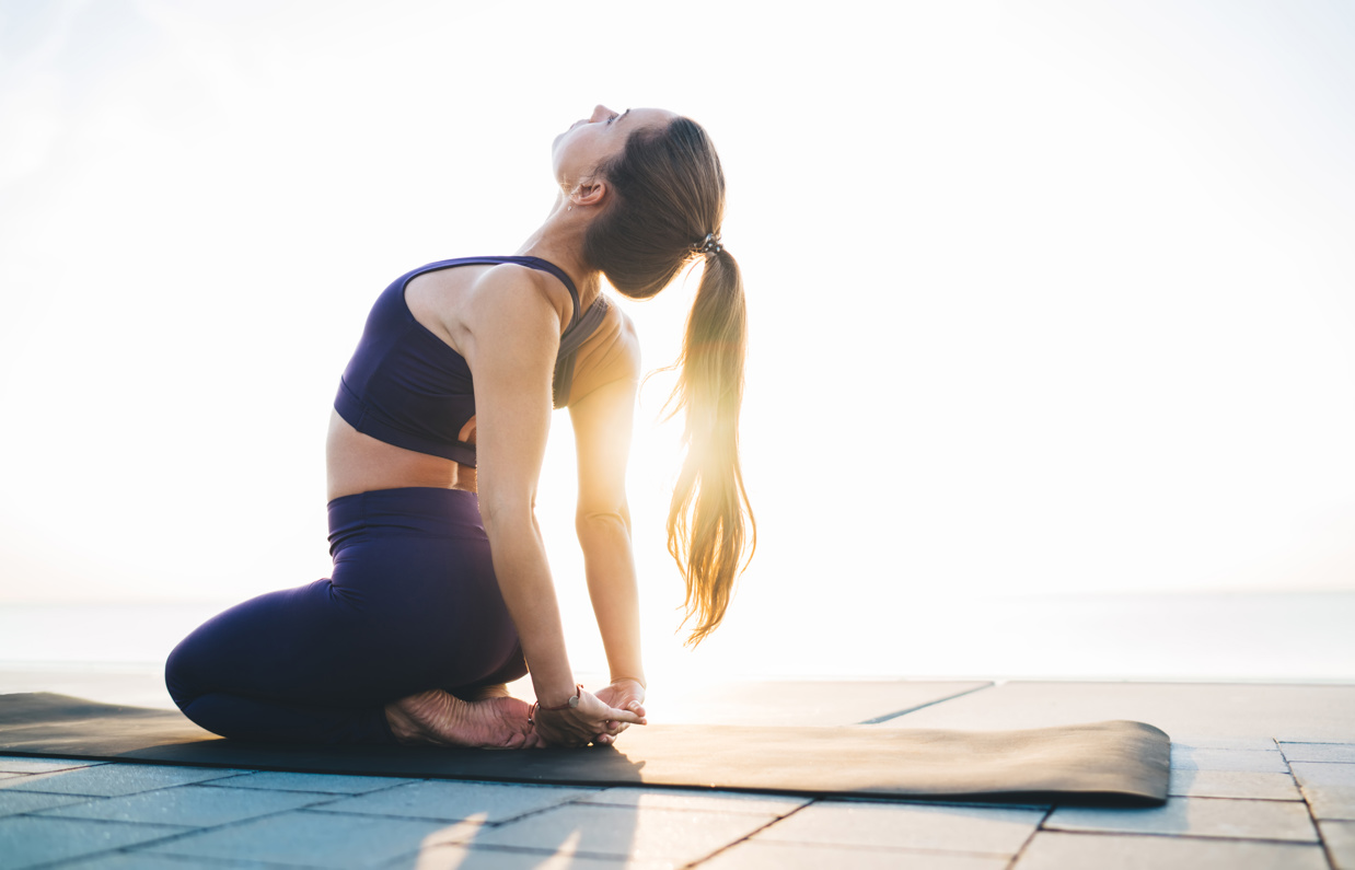 A woman stretching on a yoga mat in the sun