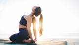 A woman stretching on a yoga mat in the sun