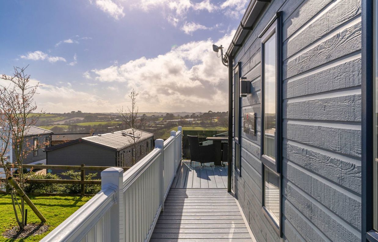 External of a caravan on pitch with decking, outdoor furniture and countryside views