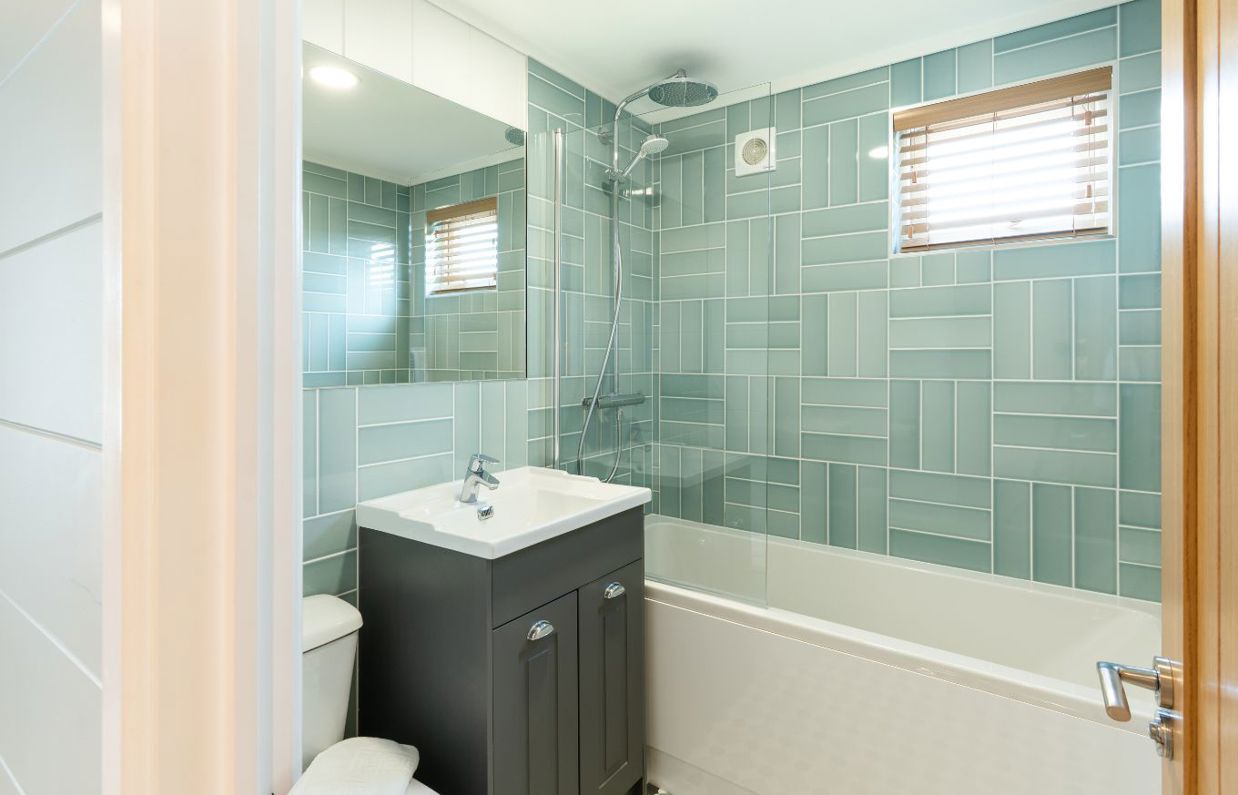 Internal of a luxury lodge bathroom with shower over bath, toilet and sink