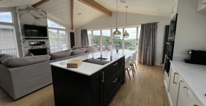 Modern open-plan kitchen island overlooking the lounge with large fireplace