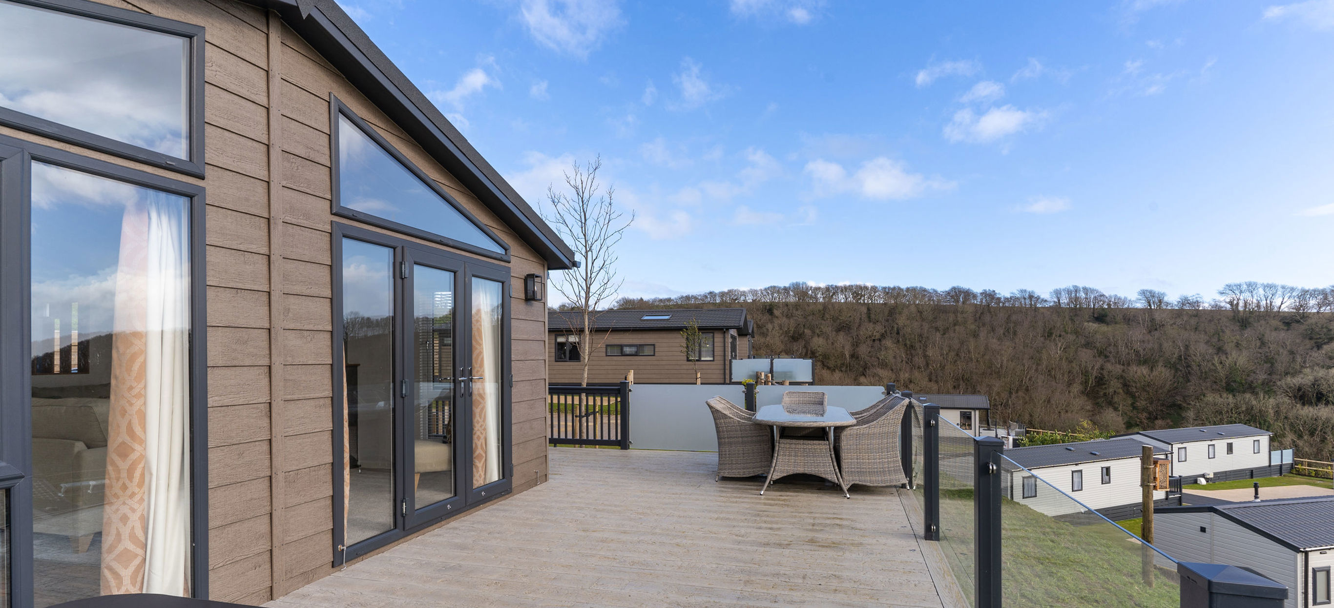 Large decking with hot tub and table and chairs outside of holiday lodge