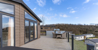 Large decking with hot tub and table and chairs outside of holiday lodge
