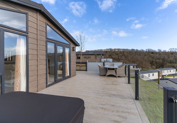 Large decking with hot tub and table and chairs outside of holiday lodge