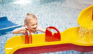 Young girl playing in splash pool