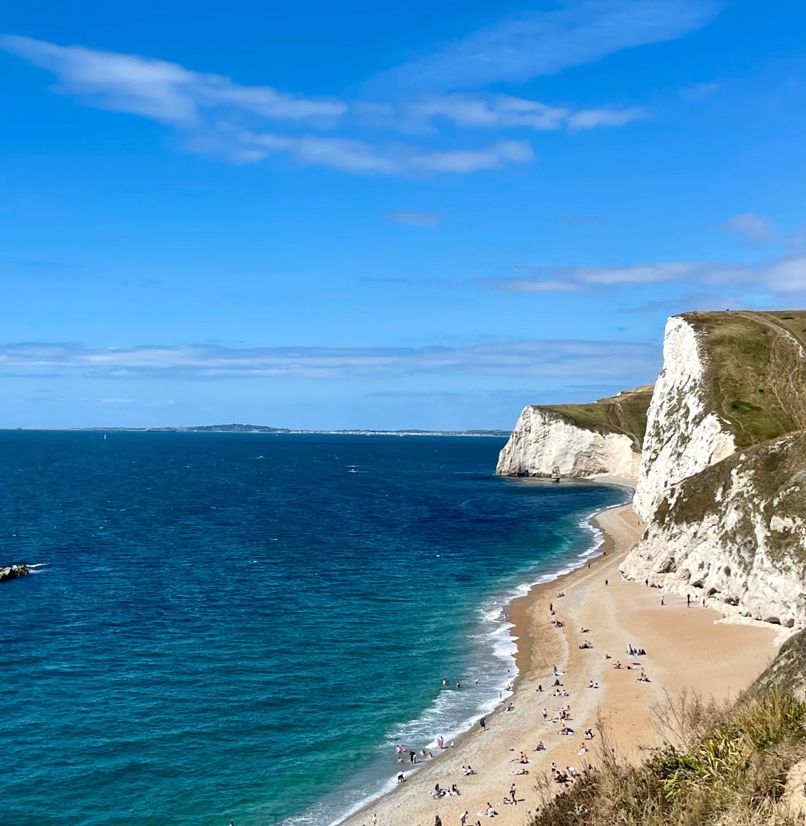 Durdle Door Beach and beyond on a sunny blue sky day with calm turquoise waters