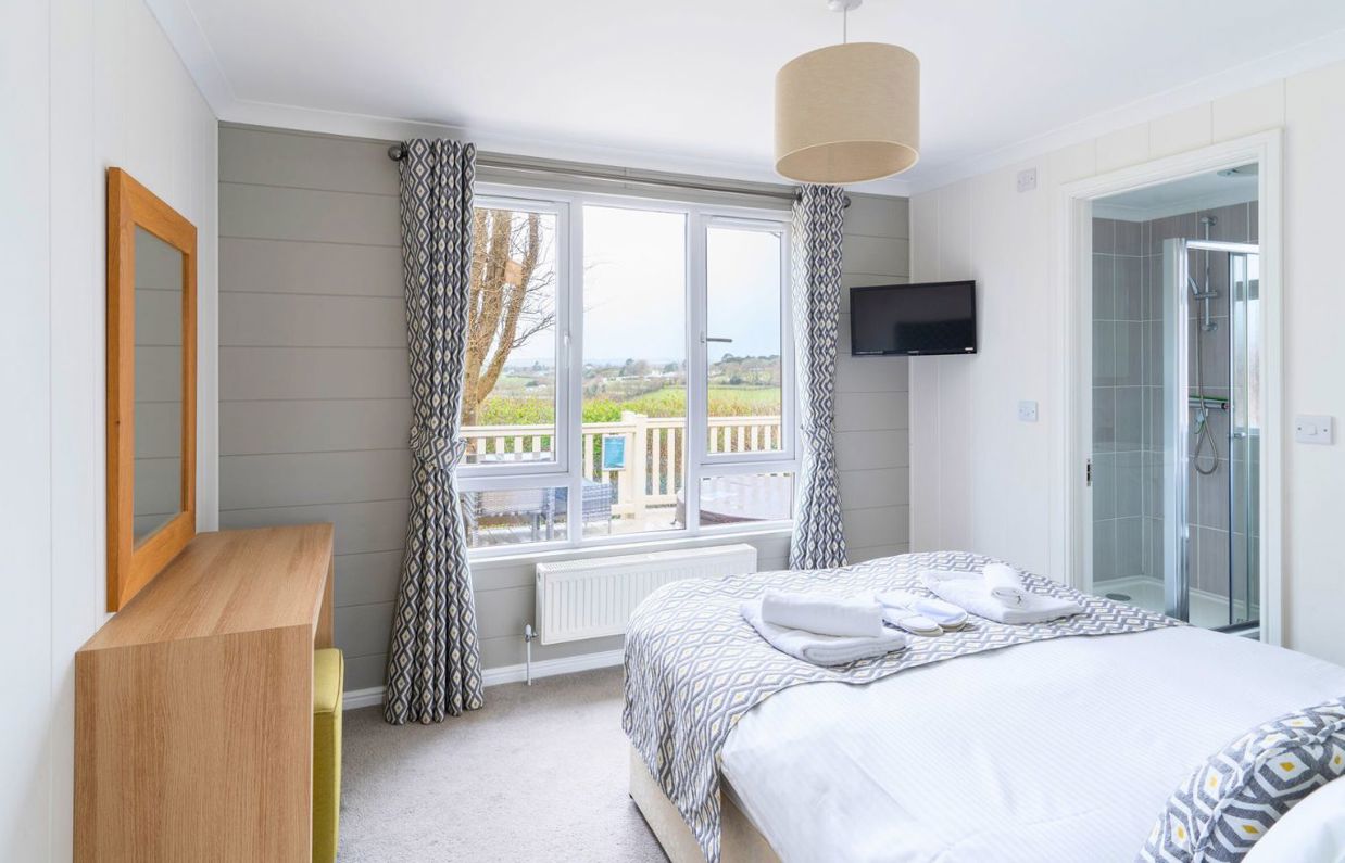 Internal of a lodge master bedroom with dressing area, ensuite and countryside views
