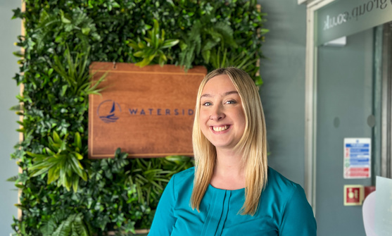 A smiling lady stood beside a Waterside sign