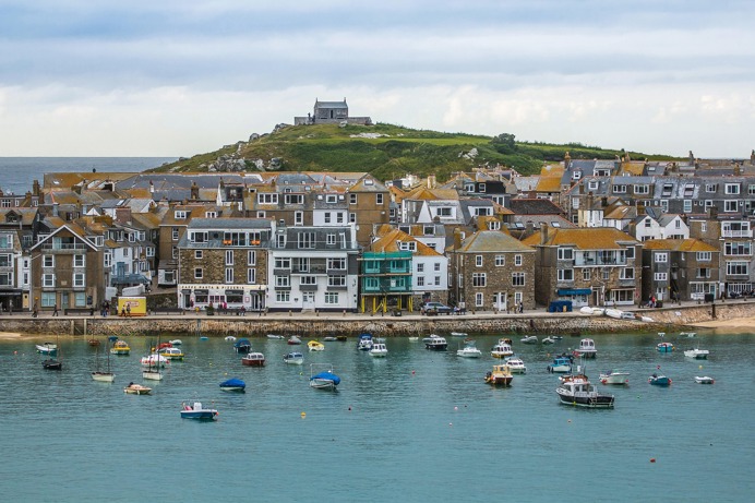 A harbourside with boats in the water and a hilltop in the background at St Ives