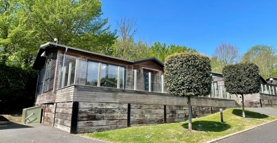 External of a luxury lodge on park with decking and surrounding trees