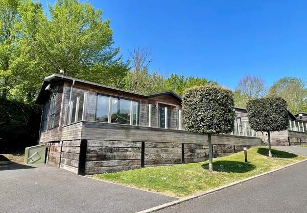 External of a luxury lodge on park with decking and surrounding trees