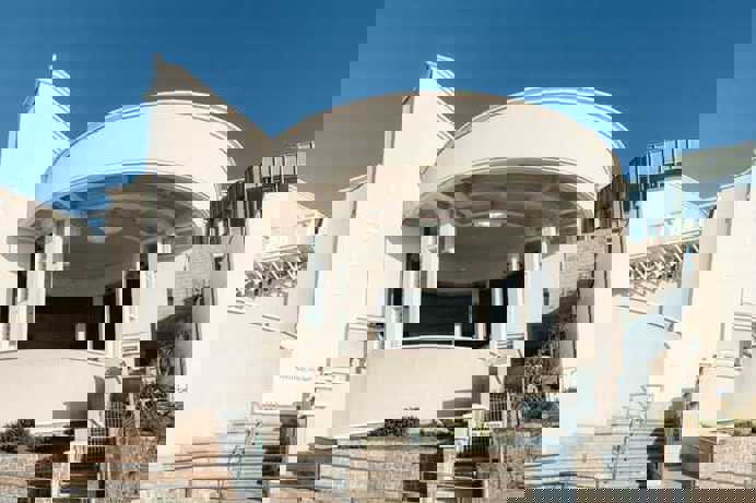 The outside of a striking art gallery building with white walls and a curved entrance