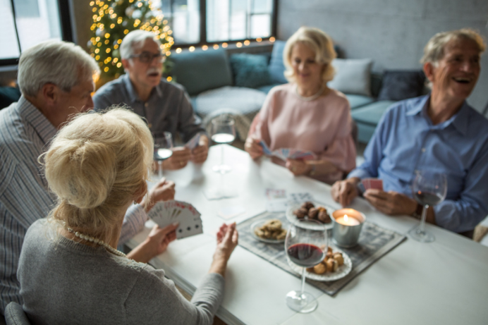 A group of older people gathered around a table at Christmas time playing games and eating and drinking