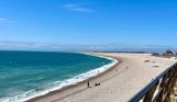 Chesil Cove Beach with striking blue water from the bottom of Portland with Weymouth in the distance