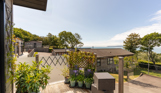 The view of the sea and Weymouth from the Kingfisher area of Osmington Mills Lodge Park surrounded by lodges and trees on a sunny, blue sky day