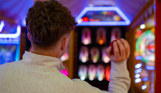 A young man throwing a ball at a Down the Clown arcade game