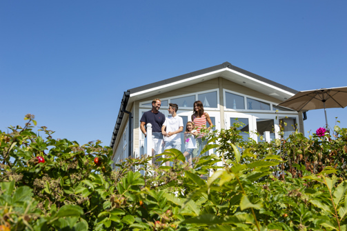 Family on deck of caravan at chesil beach looking out at the view together
