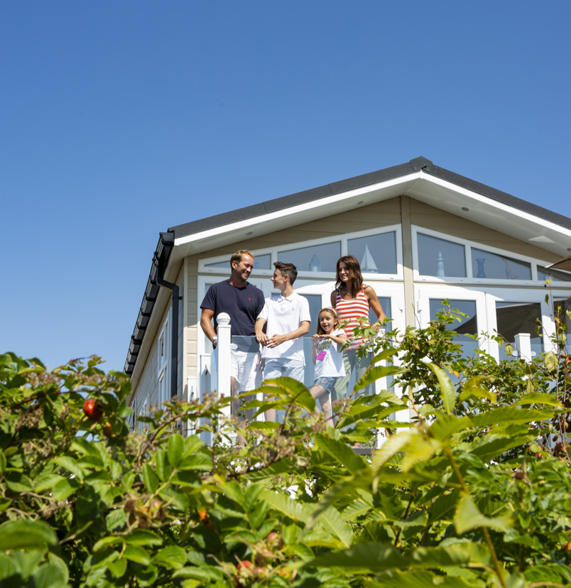 Family on deck of caravan at chesil beach looking out at the view together