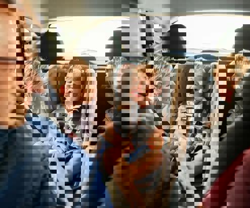 A family of five sat in a car together with the children looking distressed and bored