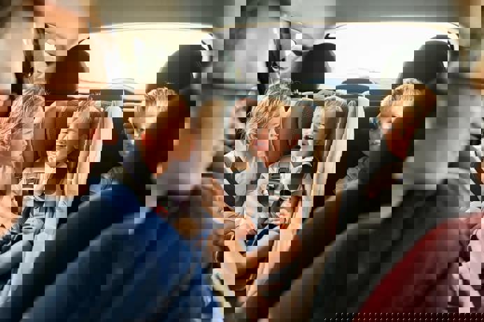 A family of five sat in a car together with the children looking distressed and bored