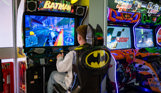 A young man sat playing a batman arcade game