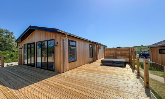 External of a luxury lodge on pitch with decking and hot tub