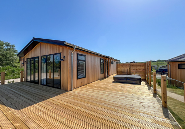 External of a luxury lodge on pitch with decking and hot tub