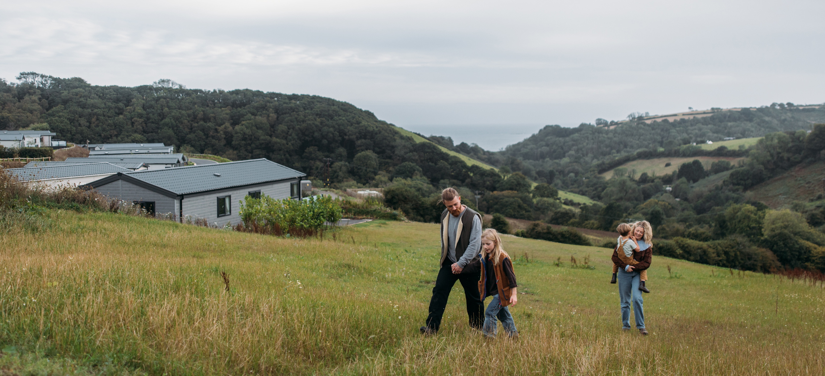 Family walking next to Seaton Sands development with valley views behind them