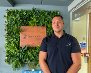A smiling man stood beside a Waterside sign