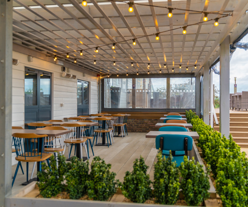 Outdoor seating under a terrace at Breeze Bar & Grill within Chesil Beach Holiday Park 