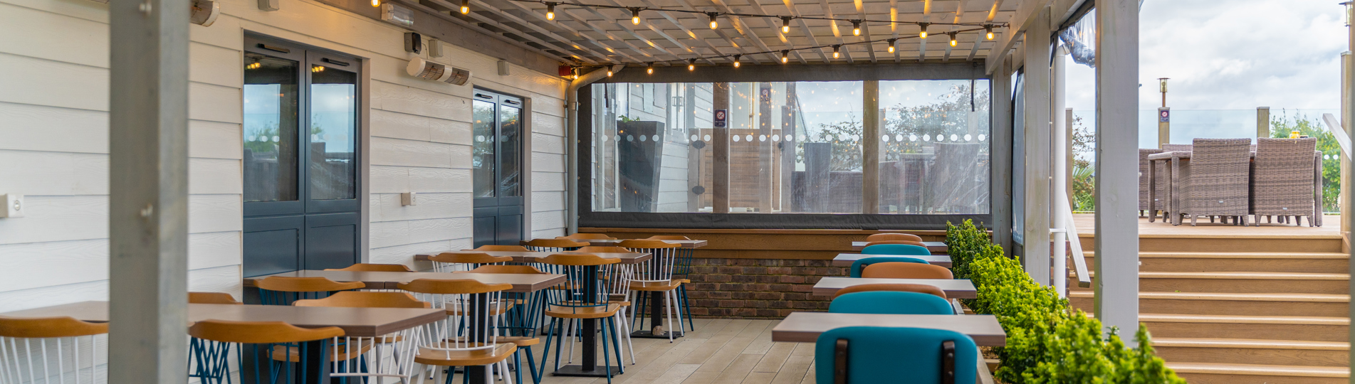 Outdoor seating under a terrace at Breeze Bar & Grill within Chesil Beach Holiday Park 