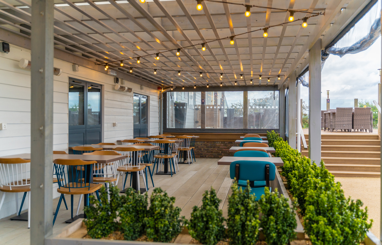 Outdoor seating under a terrace at Breeze Bar & Grill within Chesil Beach Holiday Park 