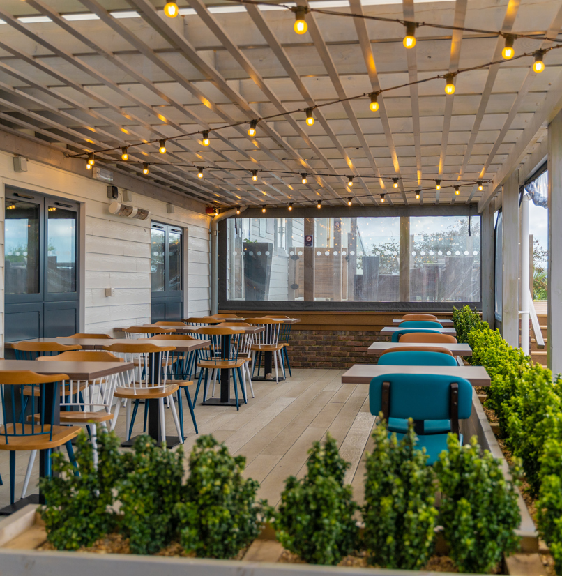 Outdoor seating under a terrace at Breeze Bar & Grill within Chesil Beach Holiday Park 