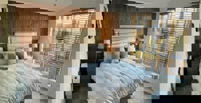 Master bedroom with wood panelling and muted tone decor