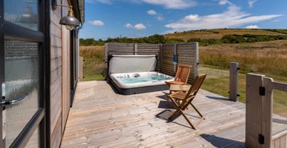 External of a cabin with decking, hot tub and outdoor furniture