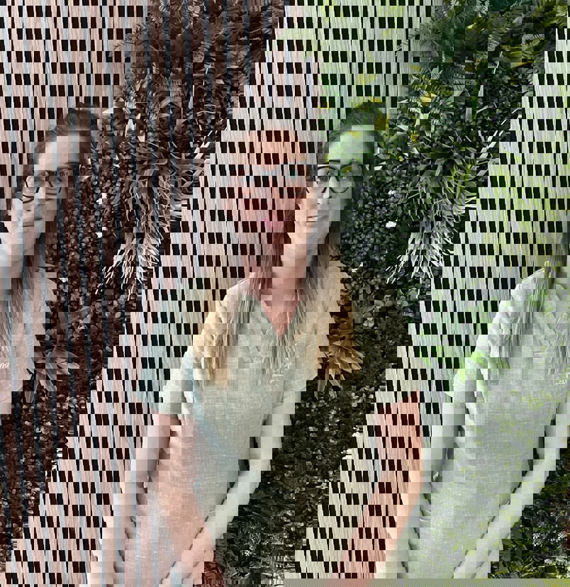 A lady smiling in spa uniform against a greenery / walnut decór background