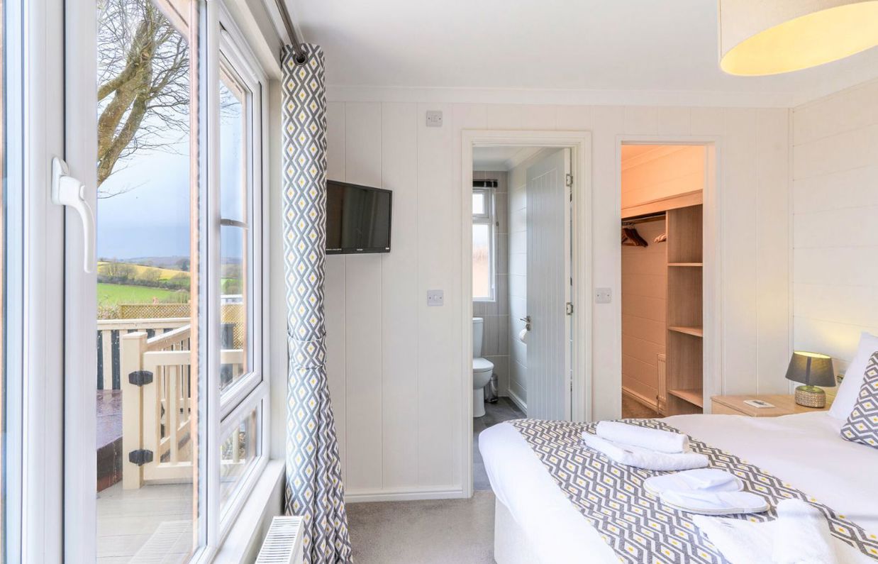 Internal of a lodge master bedroom with walk-in wardrobe, TV and ensuite