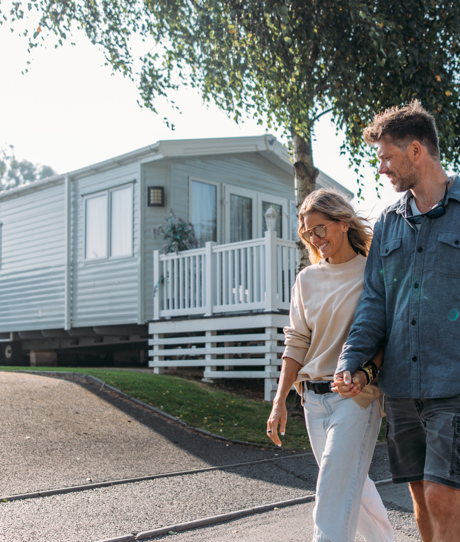 Couple walking down lane between caravans on-park
