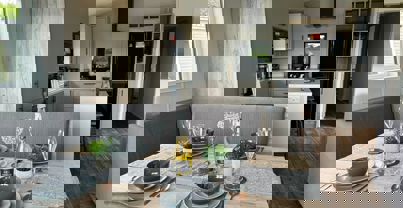 Dining table set for dinner for four people with a view through to kitchen